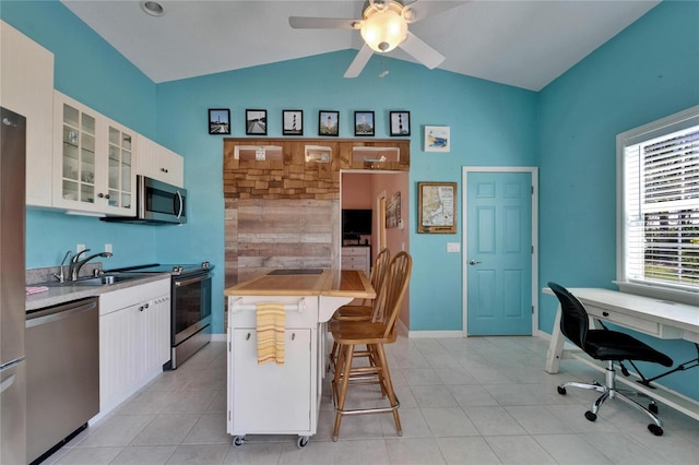 kitchen with a kitchen breakfast bar, a sink, lofted ceiling, a ceiling fan, and appliances with stainless steel finishes