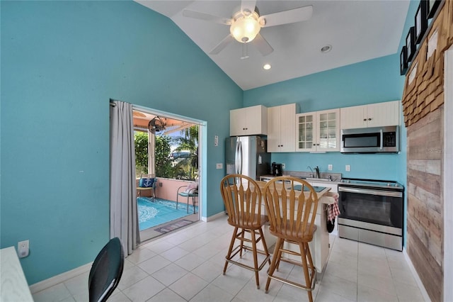 kitchen with white cabinets, stainless steel appliances, a breakfast bar, glass insert cabinets, and ceiling fan