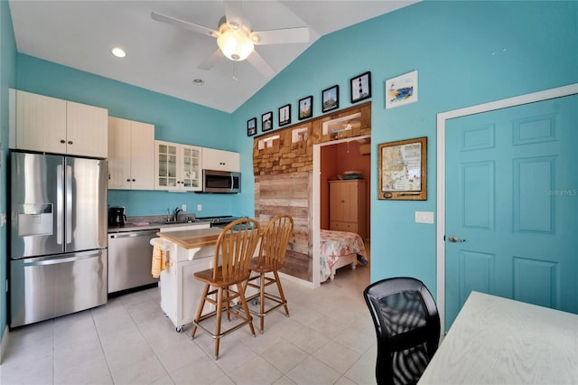 kitchen with a center island, a sink, a breakfast bar, glass insert cabinets, and appliances with stainless steel finishes