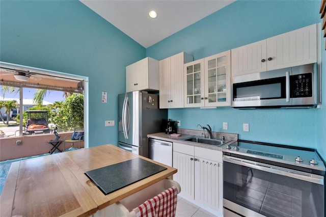 kitchen featuring stainless steel appliances, a sink, white cabinetry, glass insert cabinets, and light countertops