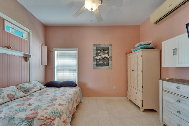 bedroom featuring light tile patterned floors, ceiling fan, baseboards, and a wall unit AC