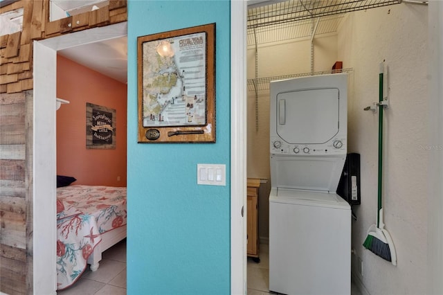 laundry room featuring tile patterned floors, stacked washer and clothes dryer, and laundry area