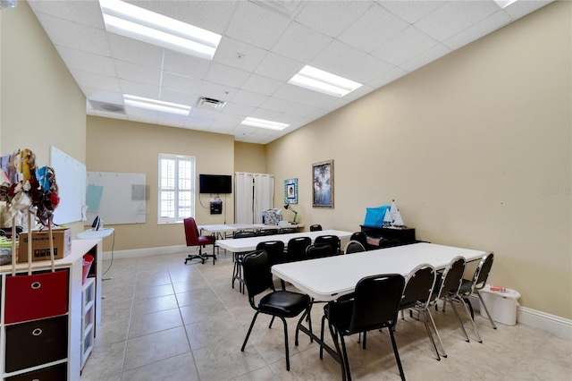tiled dining space with baseboards, visible vents, and a drop ceiling