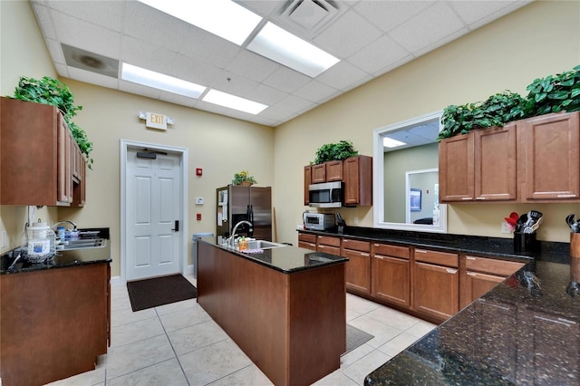kitchen featuring light tile patterned floors, stainless steel appliances, a kitchen island with sink, and a sink