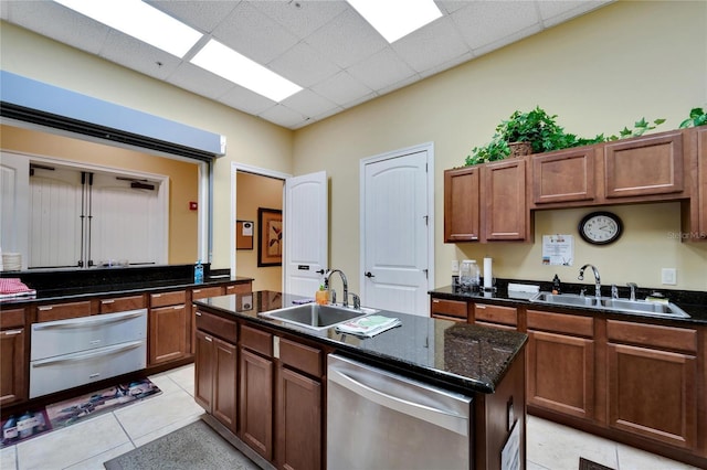 kitchen featuring a warming drawer, dishwasher, light tile patterned floors, and a sink