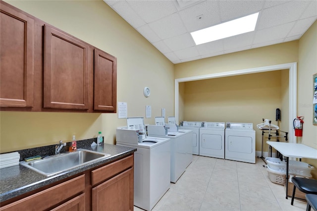 laundry area with cabinet space, light tile patterned floors, a sink, and separate washer and dryer