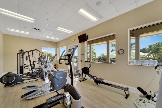 exercise room with a wealth of natural light, wood finished floors, visible vents, and baseboards