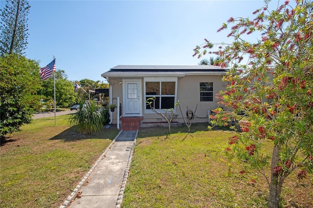2132 40th Ave N, Saint Petersburg, FL 33714 - view of front of property with roof mounted solar panels, a front lawn, and stucco siding