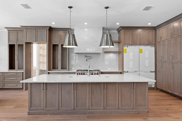 3406 W Alline Ave, Tampa, FL 33611 - kitchen with a large island with sink, decorative backsplash, light wood-style flooring, hanging light fixtures, and recessed lighting