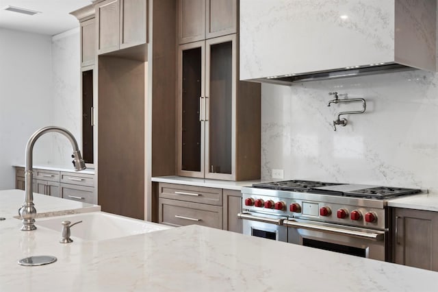 3406 W Alline Ave, Tampa, FL 33611 - kitchen with range with two ovens, tasteful backsplash, a sink, glass insert cabinets, and light stone countertops