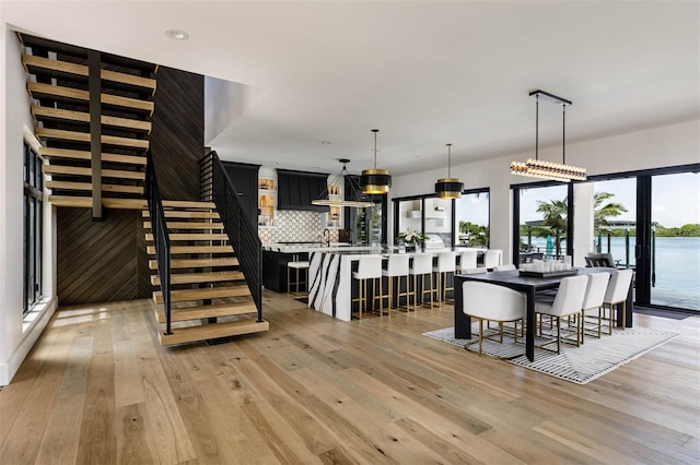 dining room featuring light wood-type flooring, recessed lighting, and stairs