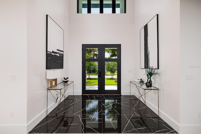 foyer featuring a towering ceiling, french doors, and baseboards