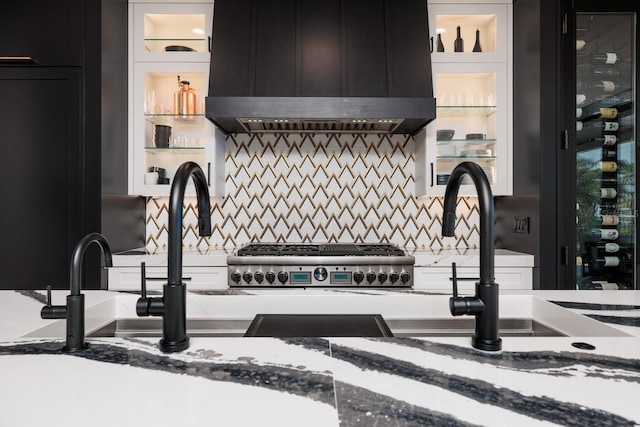 interior space featuring stone countertops, extractor fan, decorative backsplash, and dark cabinetry