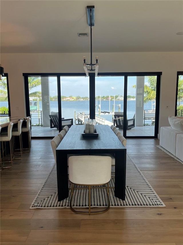 dining room with hardwood / wood-style floors, visible vents, and a water view