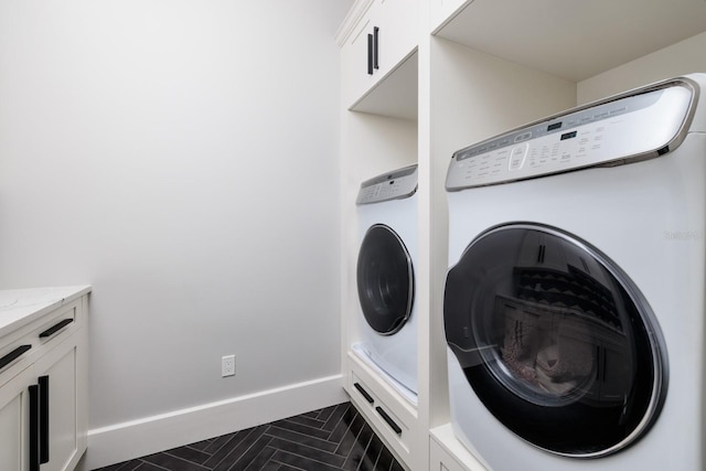 washroom with baseboards, cabinet space, and washing machine and dryer