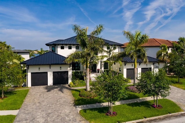 modern farmhouse featuring a standing seam roof, metal roof, stucco siding, decorative driveway, and an attached garage