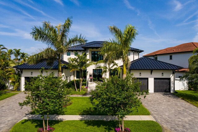 view of front of property featuring a standing seam roof, a garage, metal roof, decorative driveway, and stucco siding
