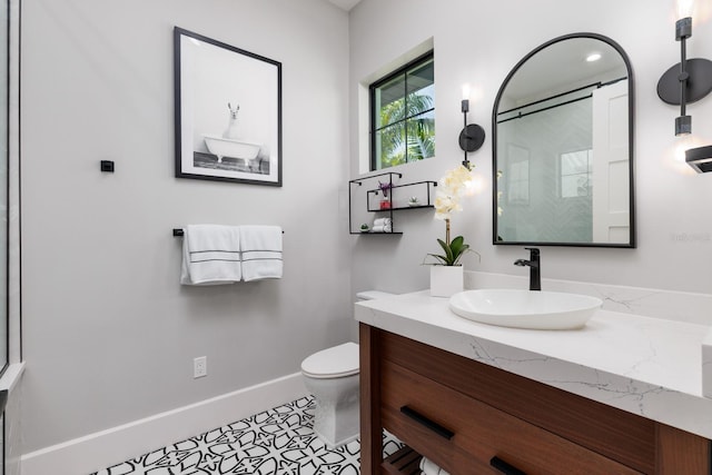 bathroom featuring vanity, toilet, a shower, baseboards, and tile patterned flooring