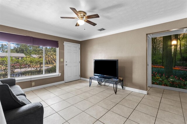 living area featuring light tile patterned floors, visible vents, baseboards, and ceiling fan