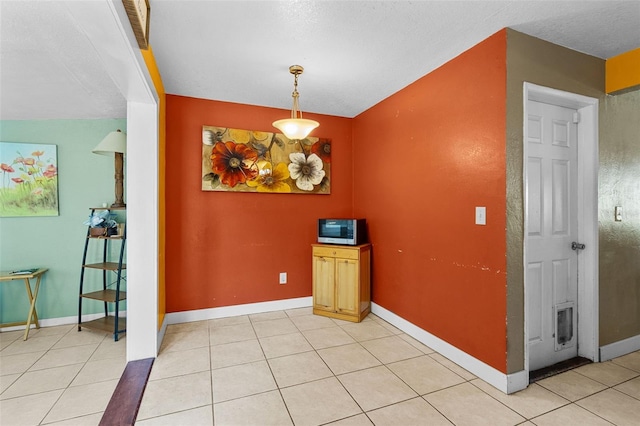 unfurnished dining area with light tile patterned floors and baseboards