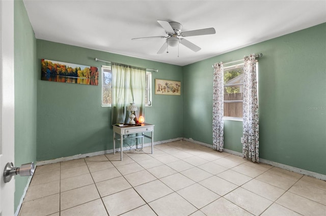 spare room with baseboards, a ceiling fan, and a wealth of natural light