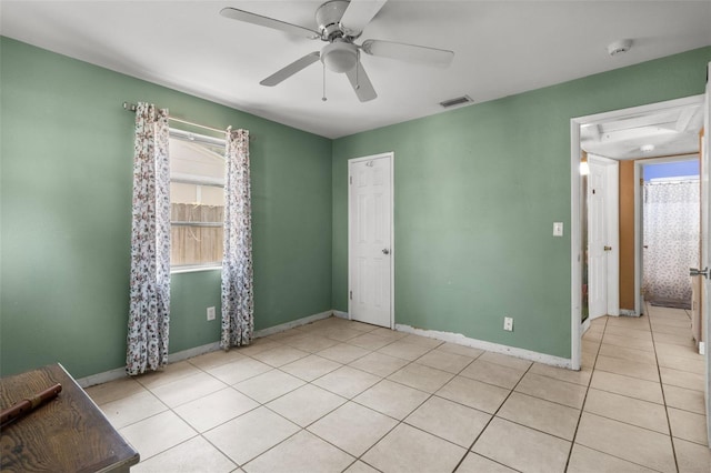 spare room featuring baseboards, a ceiling fan, light tile patterned flooring, visible vents, and a healthy amount of sunlight