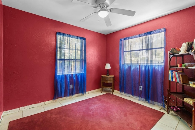 interior space with tile patterned floors, a ceiling fan, and a textured wall