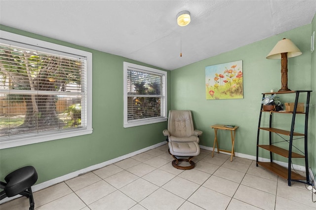 sitting room with baseboards, light tile patterned flooring, and lofted ceiling