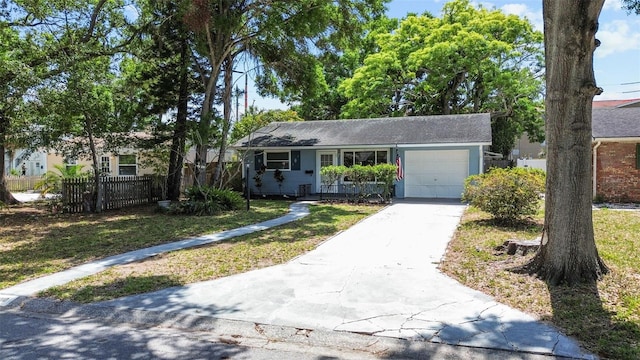 view of front facade with a front yard, fence, a garage, and concrete driveway