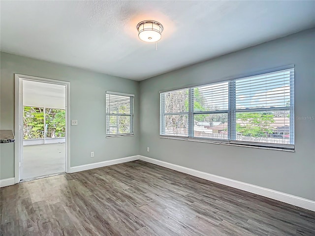 spare room with baseboards and wood finished floors