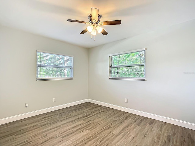 empty room featuring baseboards, a wealth of natural light, wood finished floors, and a ceiling fan
