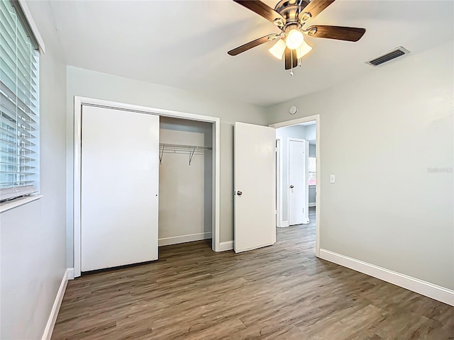 unfurnished bedroom with multiple windows, wood finished floors, a closet, and visible vents
