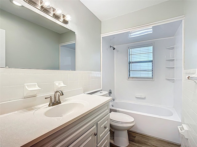 bathroom with toilet, vanity, shower / tub combination, wood finished floors, and tile walls