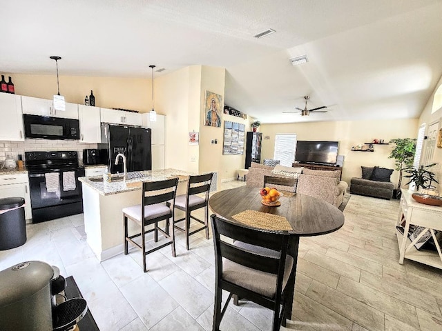 dining space featuring a ceiling fan, visible vents, and lofted ceiling