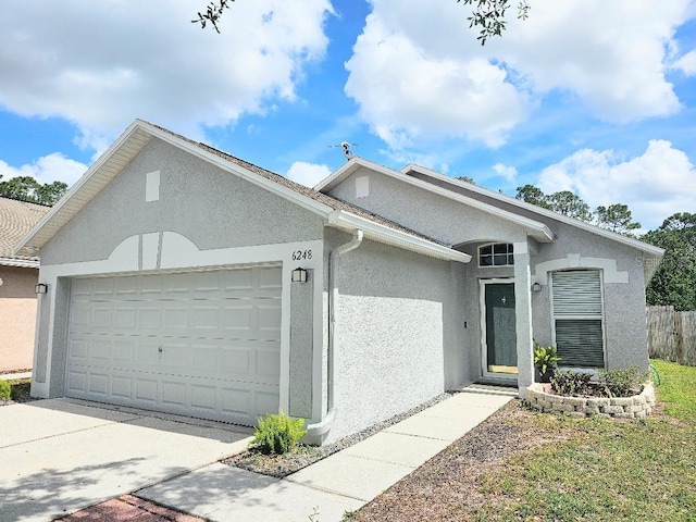 ranch-style home with an attached garage, concrete driveway, stucco siding, and fence