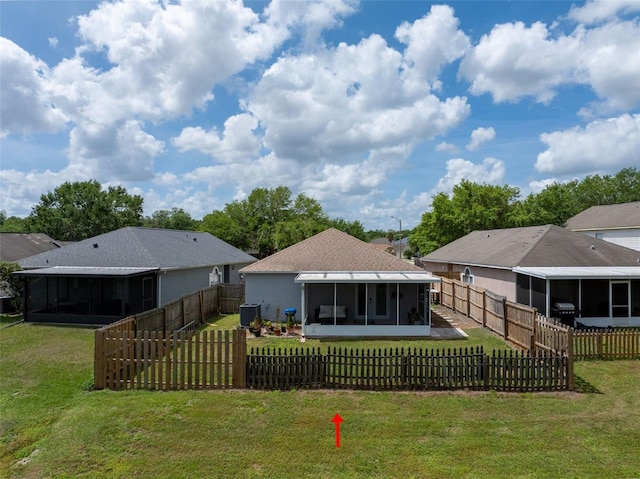 back of house with a sunroom, a lawn, and a fenced backyard