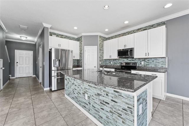 kitchen with white cabinetry, stainless steel appliances, dark stone counters, and tasteful backsplash