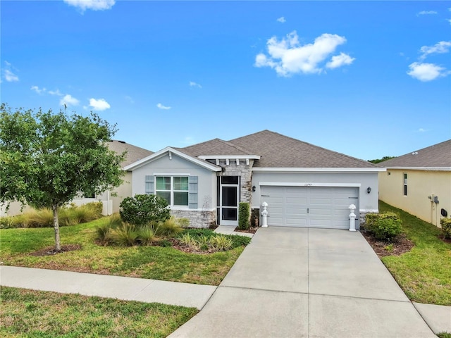 view of front of property with concrete driveway, stucco siding, a front lawn, a shingled roof, and a garage