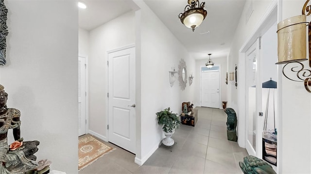hall featuring light tile patterned floors and baseboards