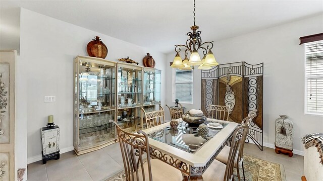dining room featuring light tile patterned floors, baseboards, and a notable chandelier