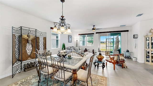 dining space with light tile patterned flooring, ceiling fan with notable chandelier, visible vents, and baseboards