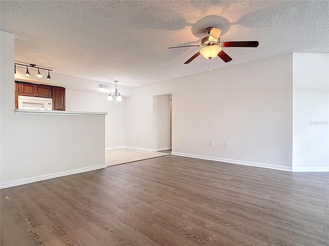 unfurnished living room featuring ceiling fan with notable chandelier, wood finished floors, and a textured ceiling