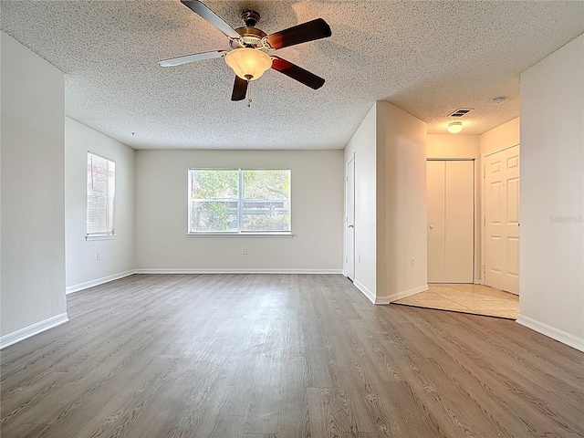unfurnished room featuring baseboards, a textured ceiling, wood finished floors, and a ceiling fan