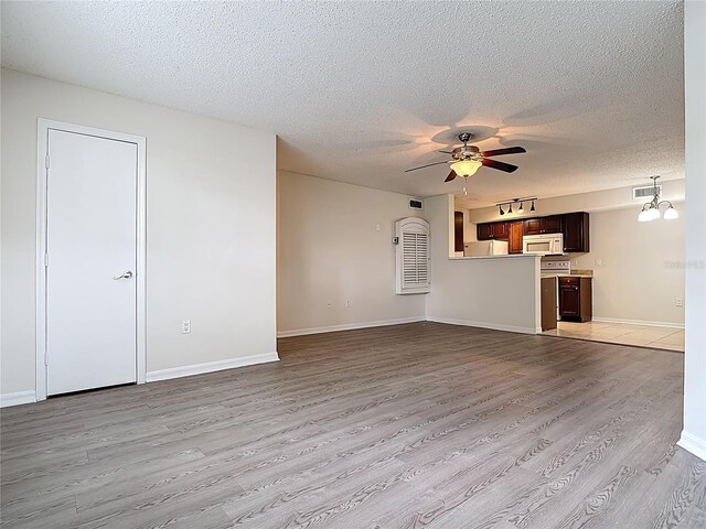 unfurnished living room featuring a textured ceiling, visible vents, light wood finished floors, baseboards, and a ceiling fan
