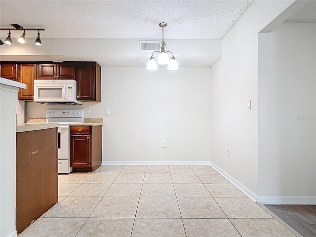 kitchen featuring a textured ceiling, visible vents, light tile patterned floors, and white appliances