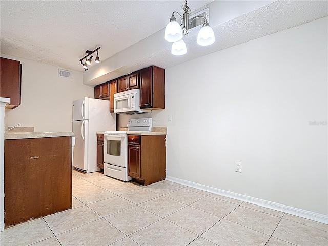 kitchen featuring light tile patterned flooring, a textured ceiling, visible vents, light countertops, and white appliances