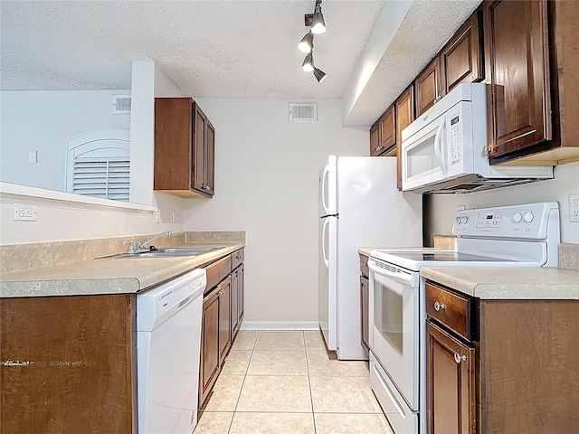 kitchen featuring white appliances, light tile patterned floors, a textured ceiling, a sink, and visible vents