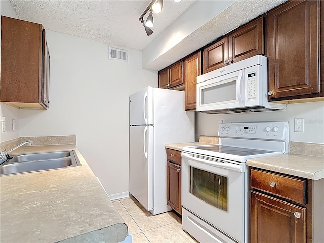 kitchen featuring white appliances, light tile patterned floors, a textured ceiling, a sink, and visible vents