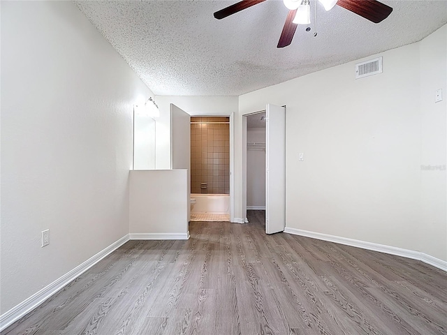 unfurnished room with baseboards, a textured ceiling, visible vents, a ceiling fan, and wood finished floors