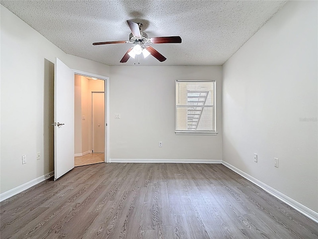 unfurnished room featuring a textured ceiling, baseboards, ceiling fan, and wood finished floors